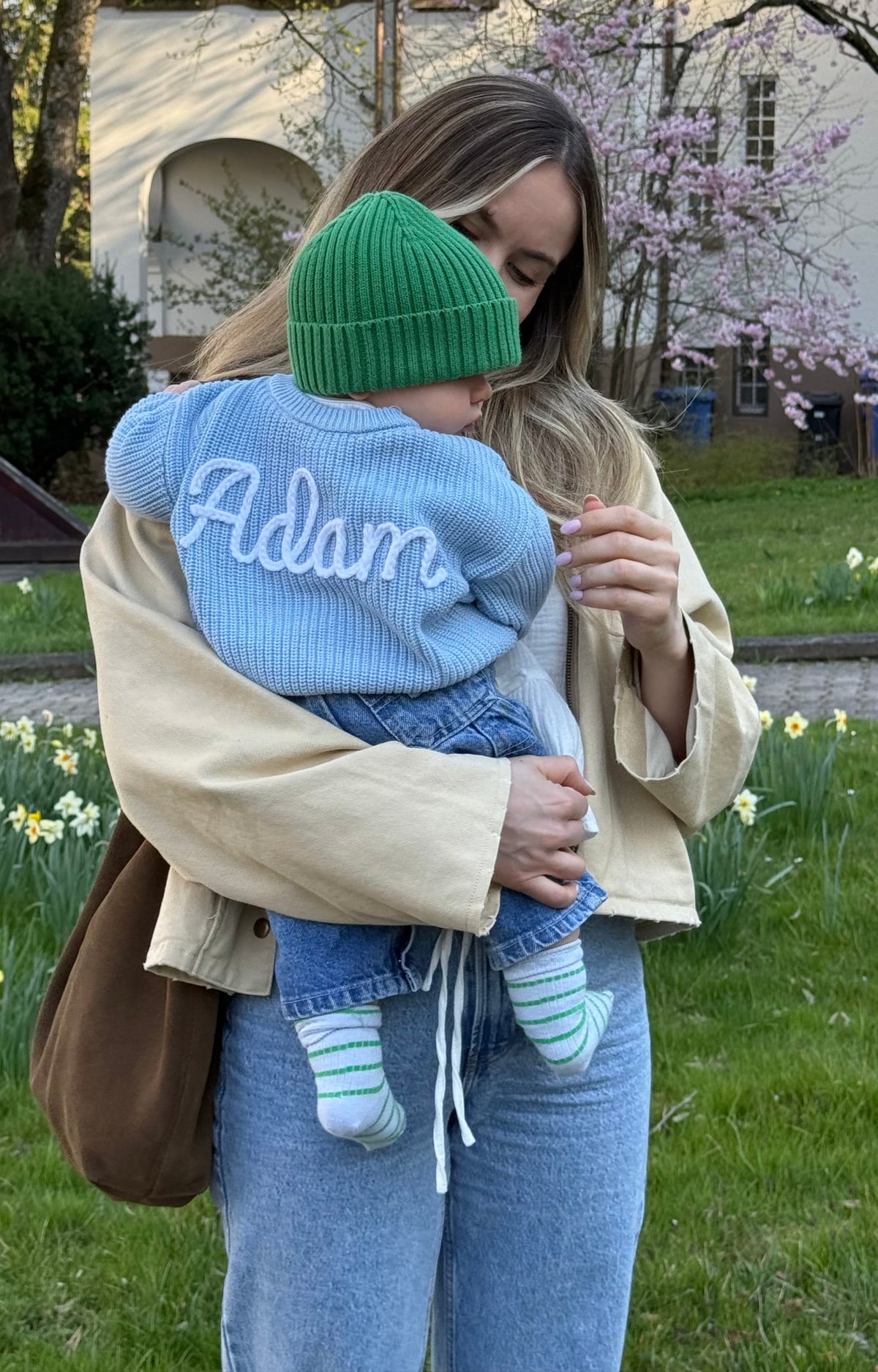 Kind im personalisierten Strickpullover mit dem Namen Adam auf dem Arm der Mutter