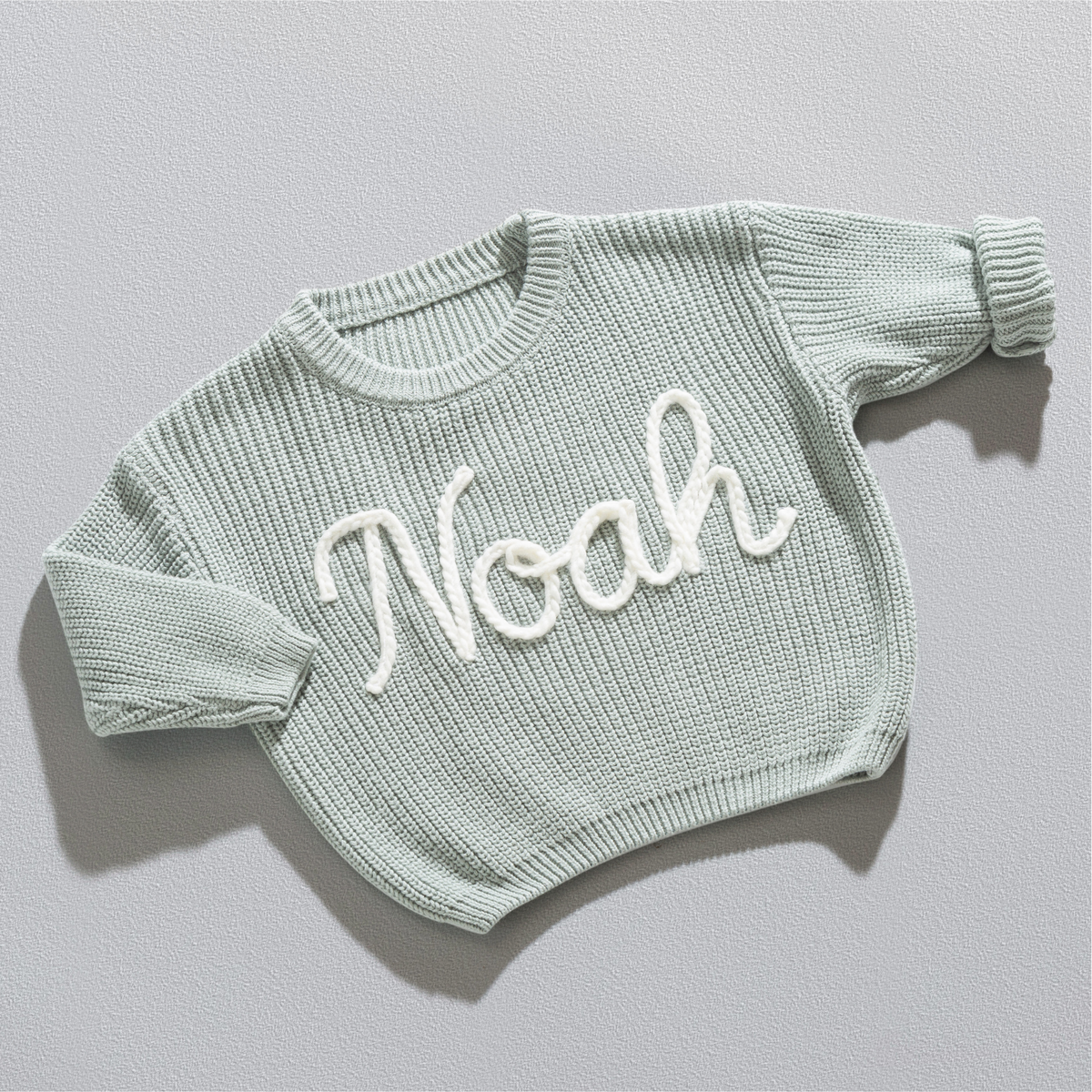Personalisierter Strickpullover in Mintgrün mit dem Namen Noah, handgestickt in Off-White